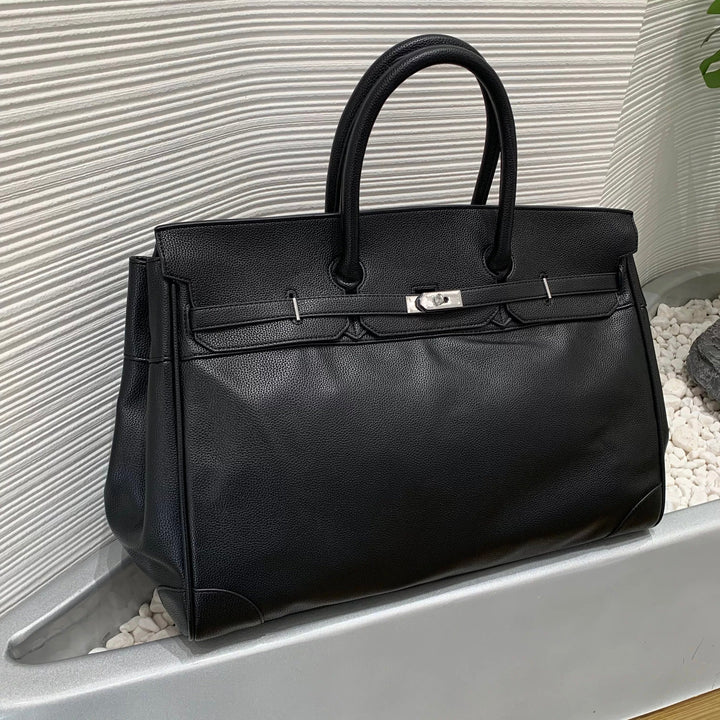 Black leather handbag with silver hardware on a textured surface
