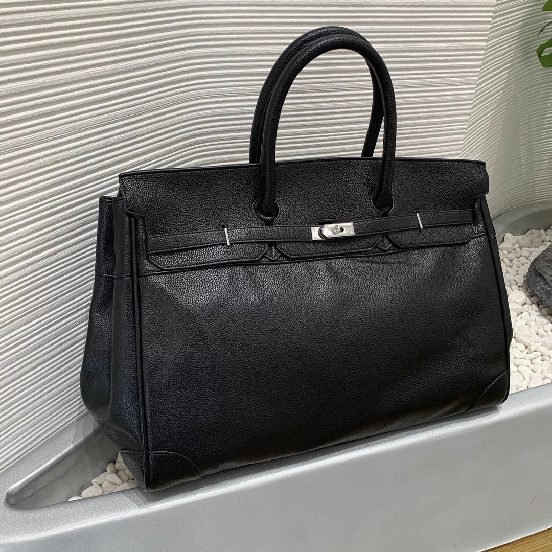 Black leather handbag with silver hardware on a textured surface