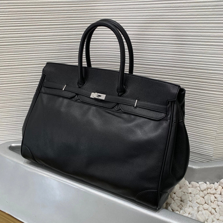 Black leather handbag with silver hardware on a textured white background