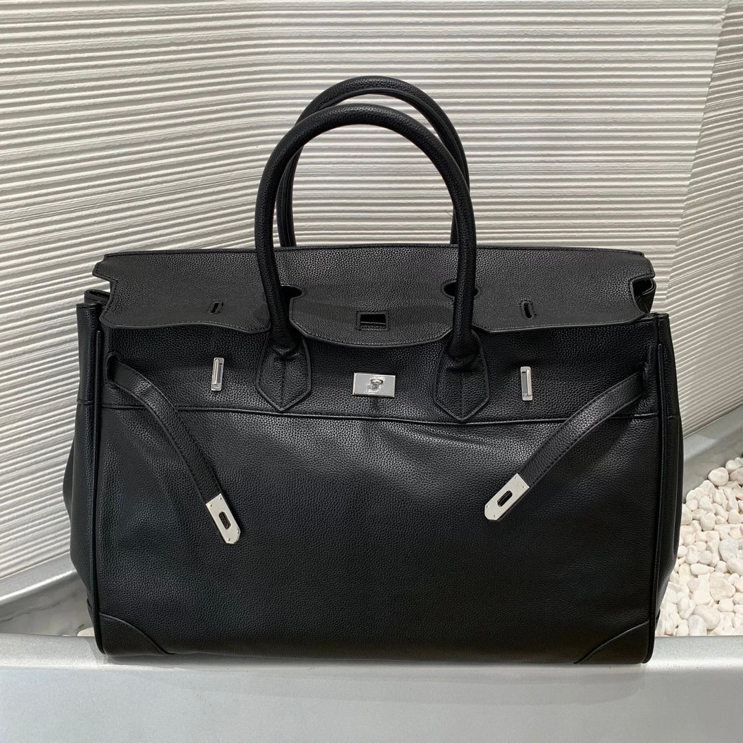 Black leather bag with silver hardware on a light gray surface.