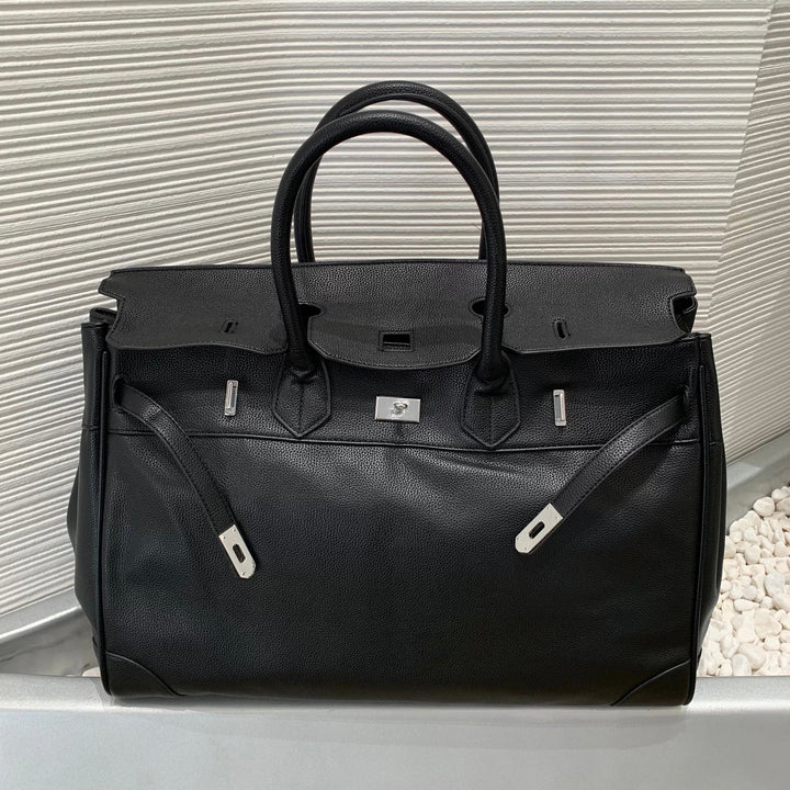 Black leather bag with silver hardware on a light gray surface.