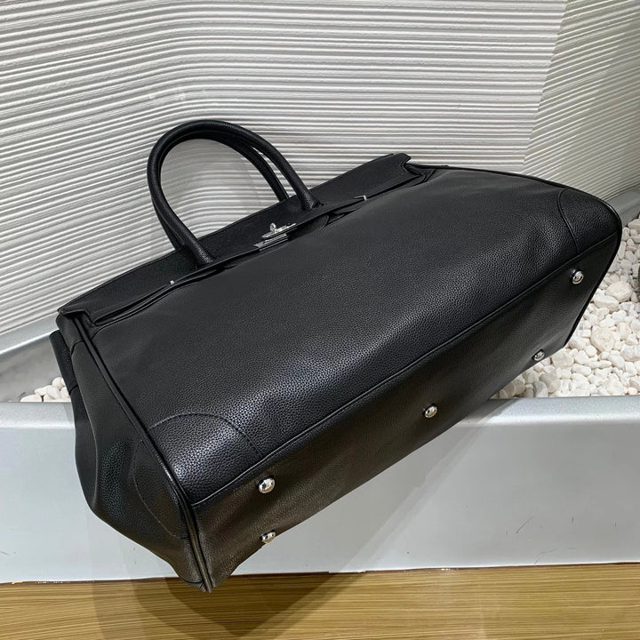 Black leather duffel bag on a textured white surface