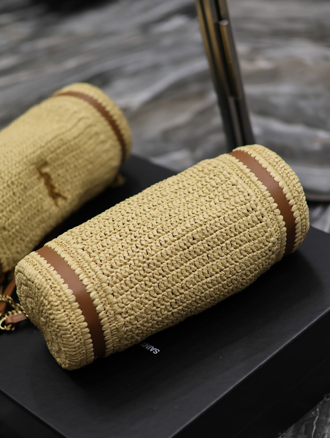 Namrico Cassandre cylinder bag close-up of braided raffia texture and bronze hardware
