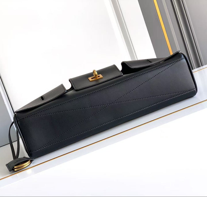 Black handbag with gold clasp on a white surface