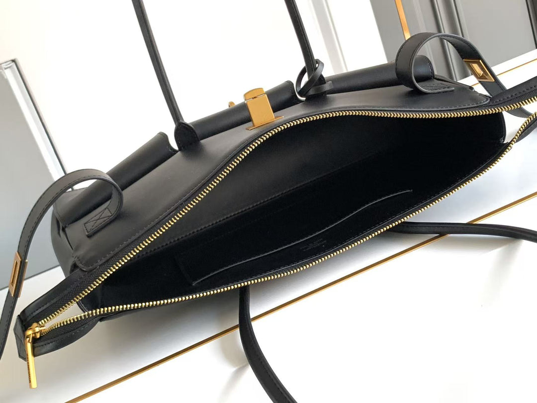 Black handbag with gold zipper and handle on a white background