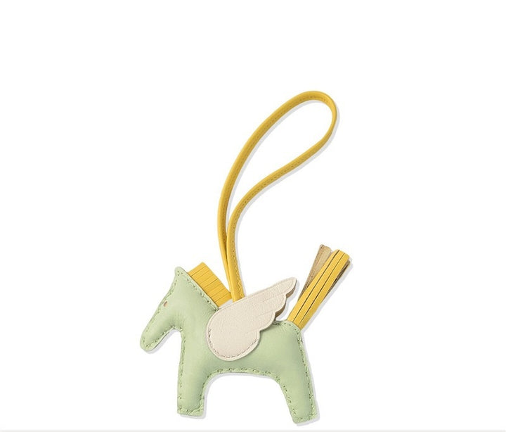 Small green plush toy with a yellow strap on a white background