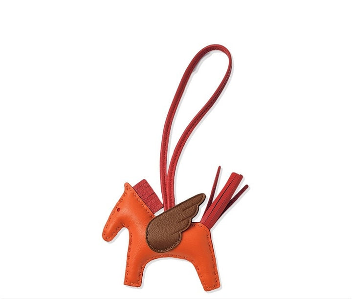 Orange and brown horse-shaped keychain with a red strap on a white background