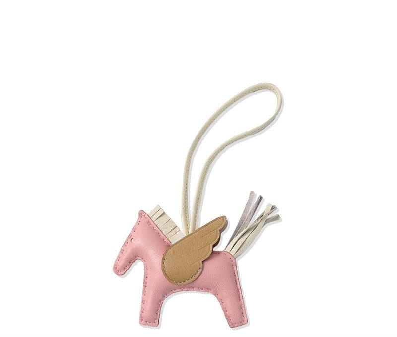 Pink horse-shaped keychain with a gold saddle on a white background