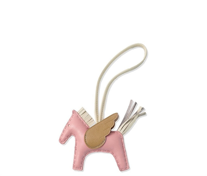 Pink horse-shaped keychain with a gold saddle on a white background
