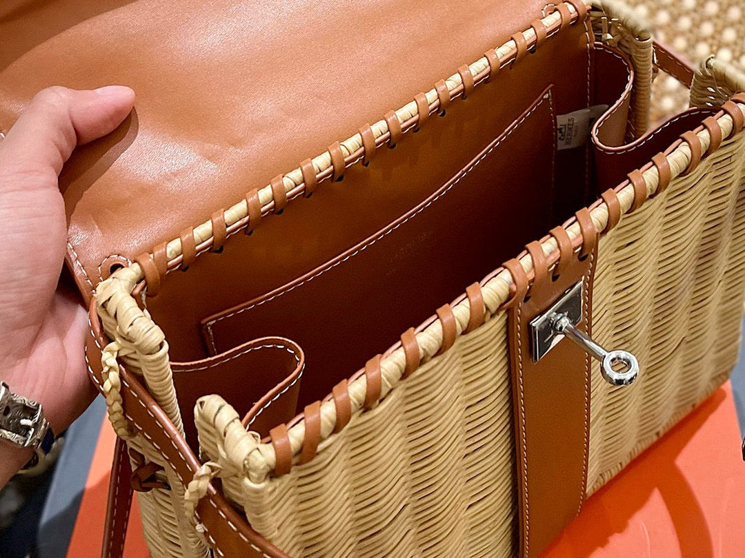 Brown leather handbag with woven details held by a hand on an orange surface.