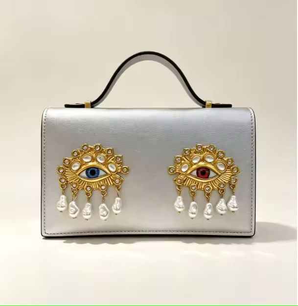 3D jewel eye shoulder bag front view showing sculptural eye embellishment and pearl accents