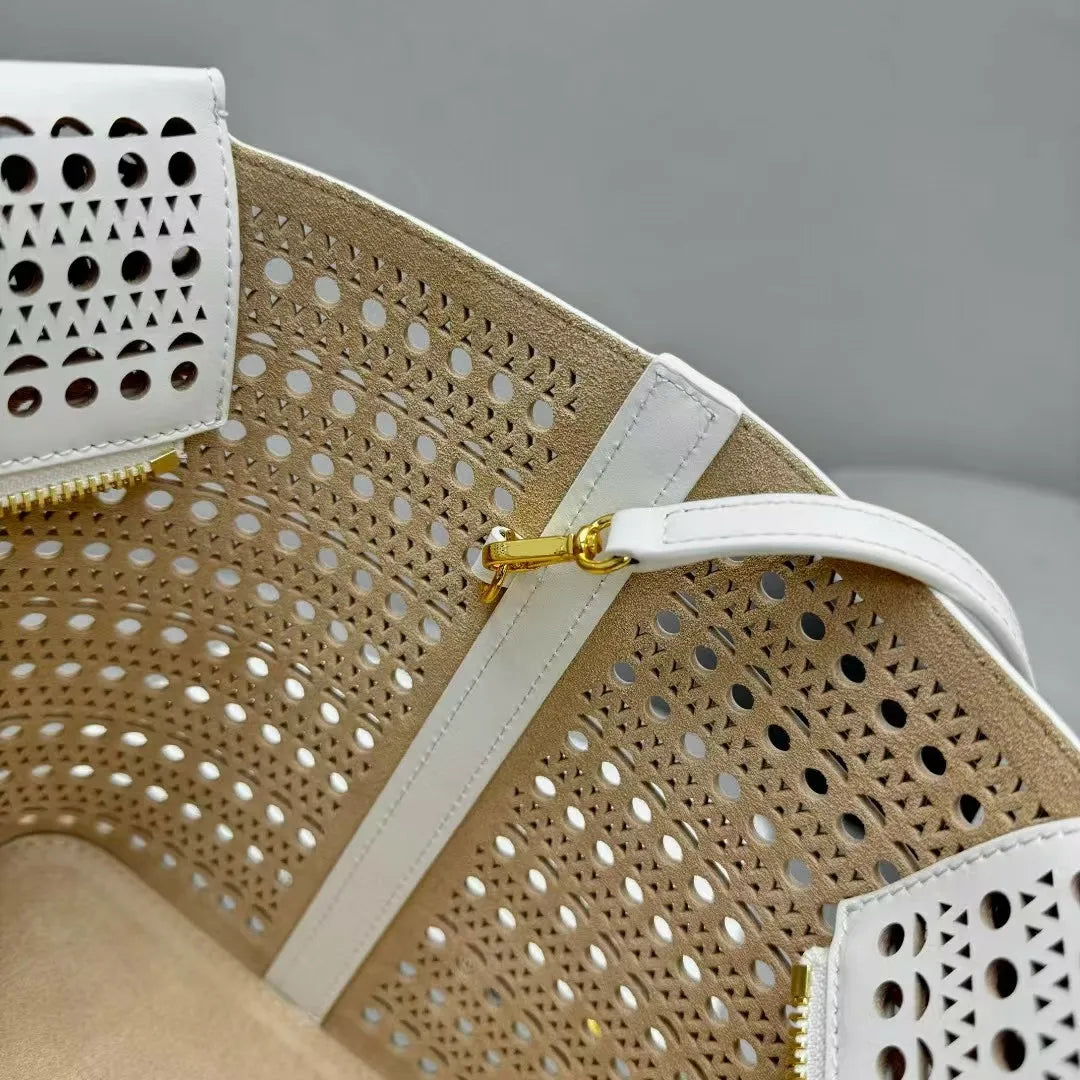 Close-up of a beige handbag with white geometric patterns and gold zipper.