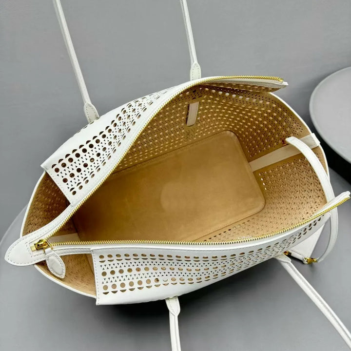 White woven bag with gold zipper on a gray background