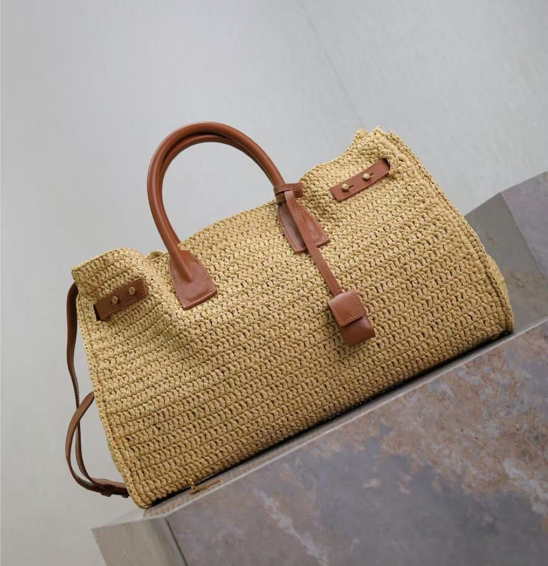 Woven handbag with brown leather straps on a stone surface