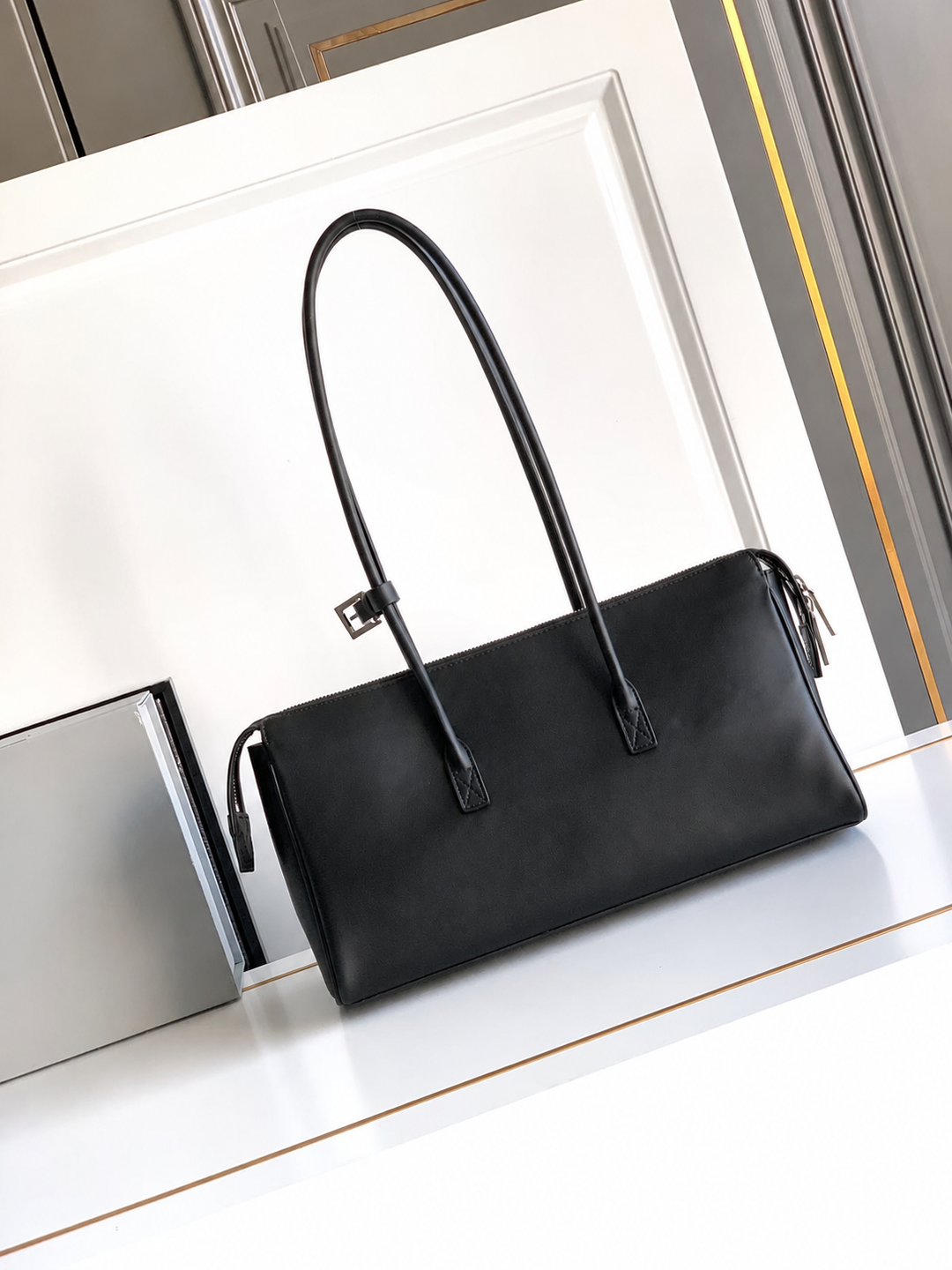 Black handbag on a white surface with a reflective background
