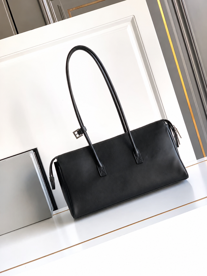 Black handbag on a white surface with a reflective background