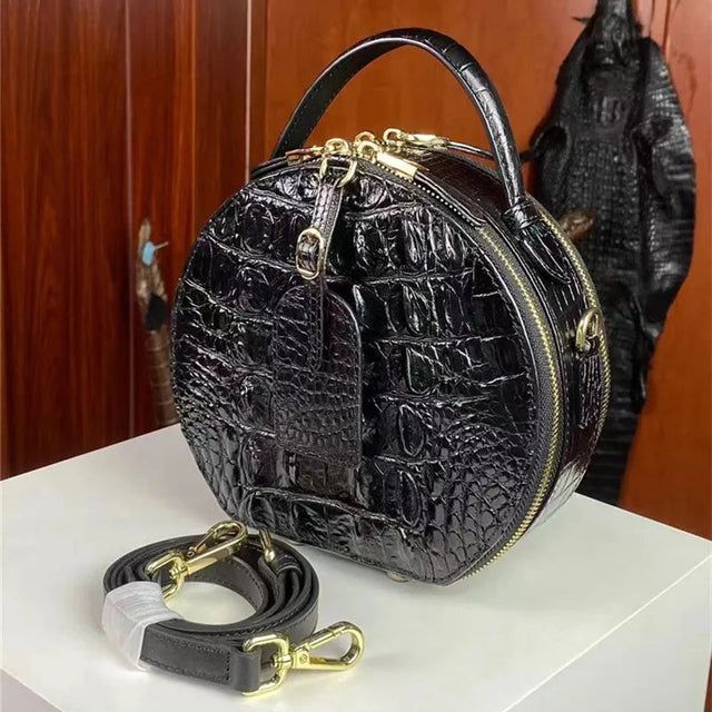 Genuine crocodile skin round bag in glossy black with gold zipper and buckle detail