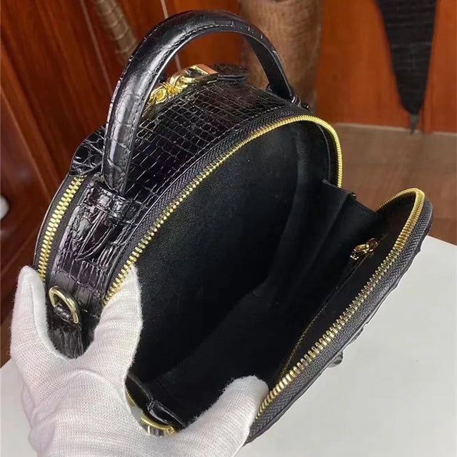 Black glossy crocodile round bag top handle view with zipper closure