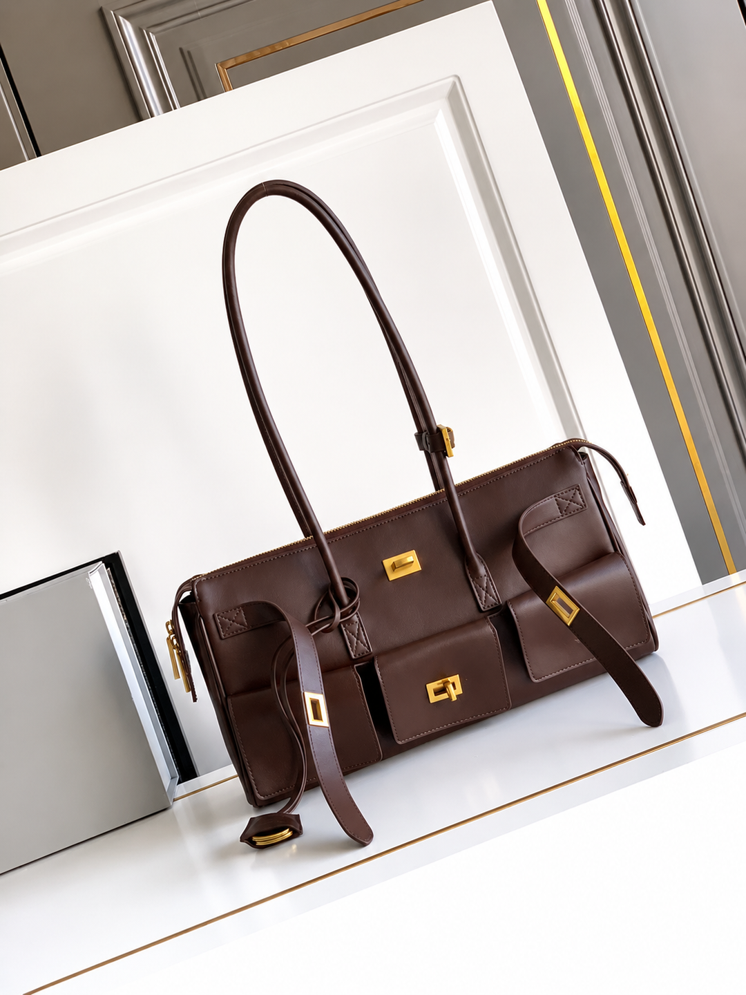 Brown handbag with gold accents on a white surface