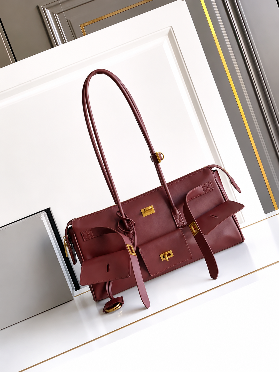 Maroon handbag with gold accents on a white surface