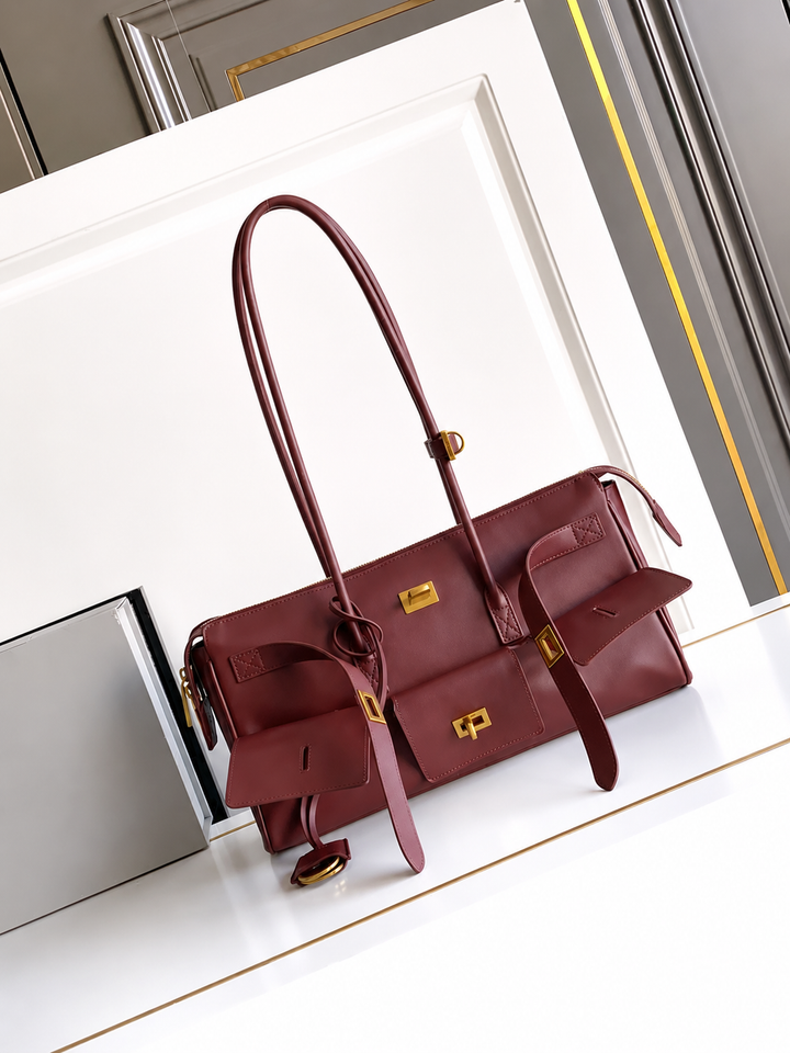 Maroon handbag with gold accents on a white surface