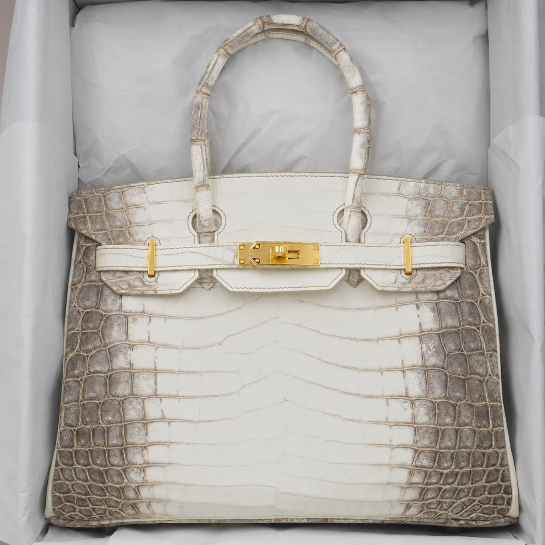 Luxury handbag with crocodile skin pattern and gold hardware on a light gray background