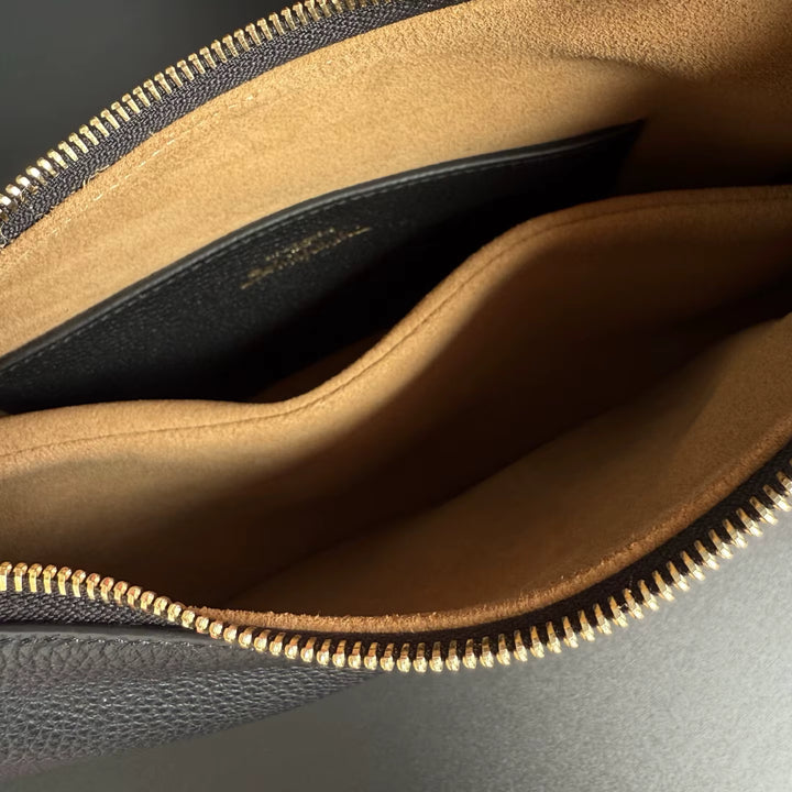 Close-up of a leather pouch with zipper, showing interior and exterior details.
