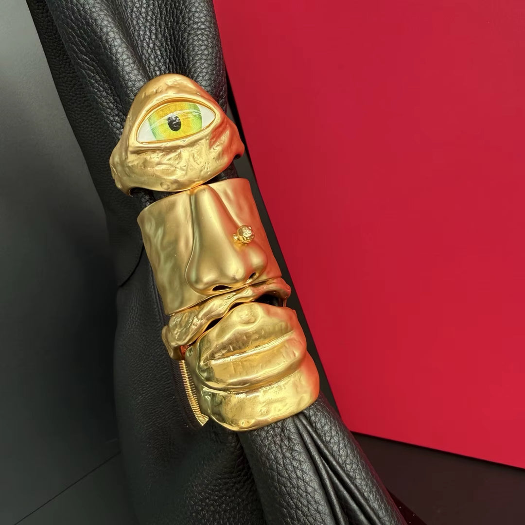 Gold decorative handle with eye design on a black object against a red background