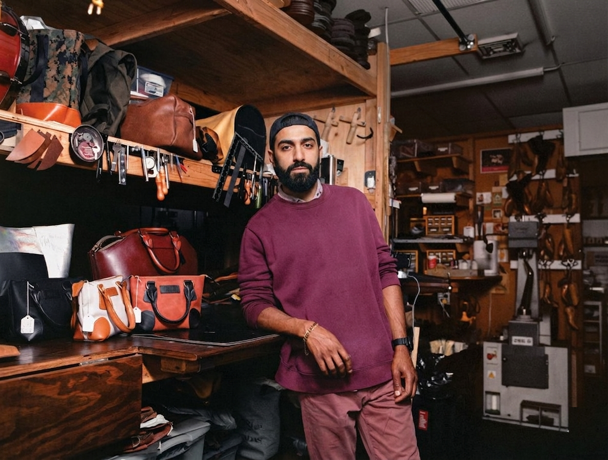 Man standing in a workshop with leather goods on shelves