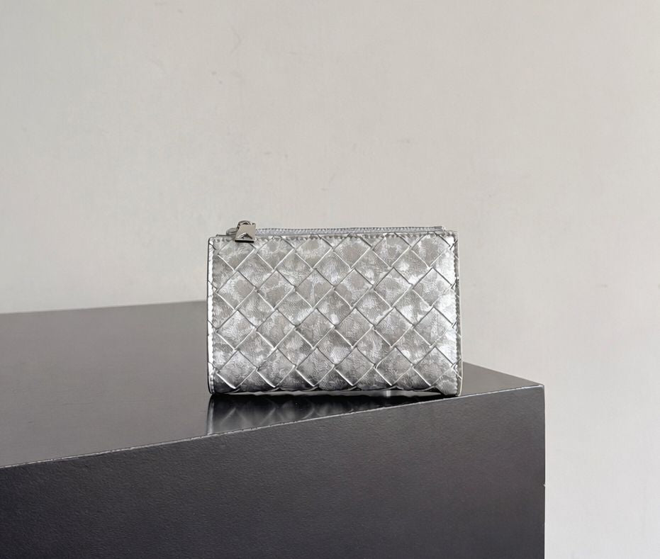 Silver quilted clutch bag on a reflective surface with a neutral background