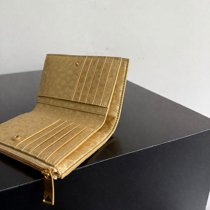 Gold wallet on a black surface with a light gray background