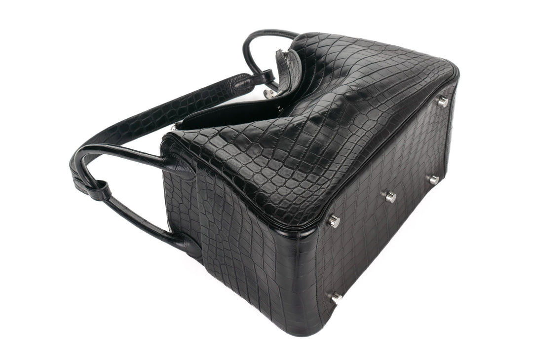 Black crocodile-patterned handbag with silver studs on a white background