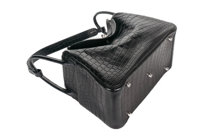 Black crocodile-patterned handbag with silver studs on a white background