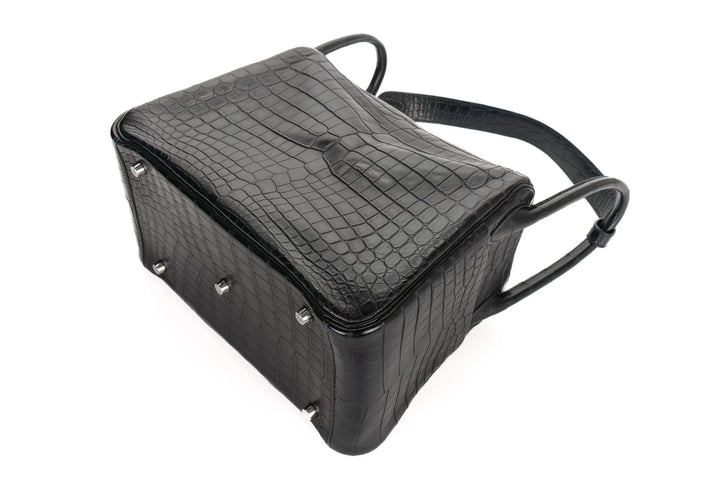 Black crocodile-patterned handbag on a white background
