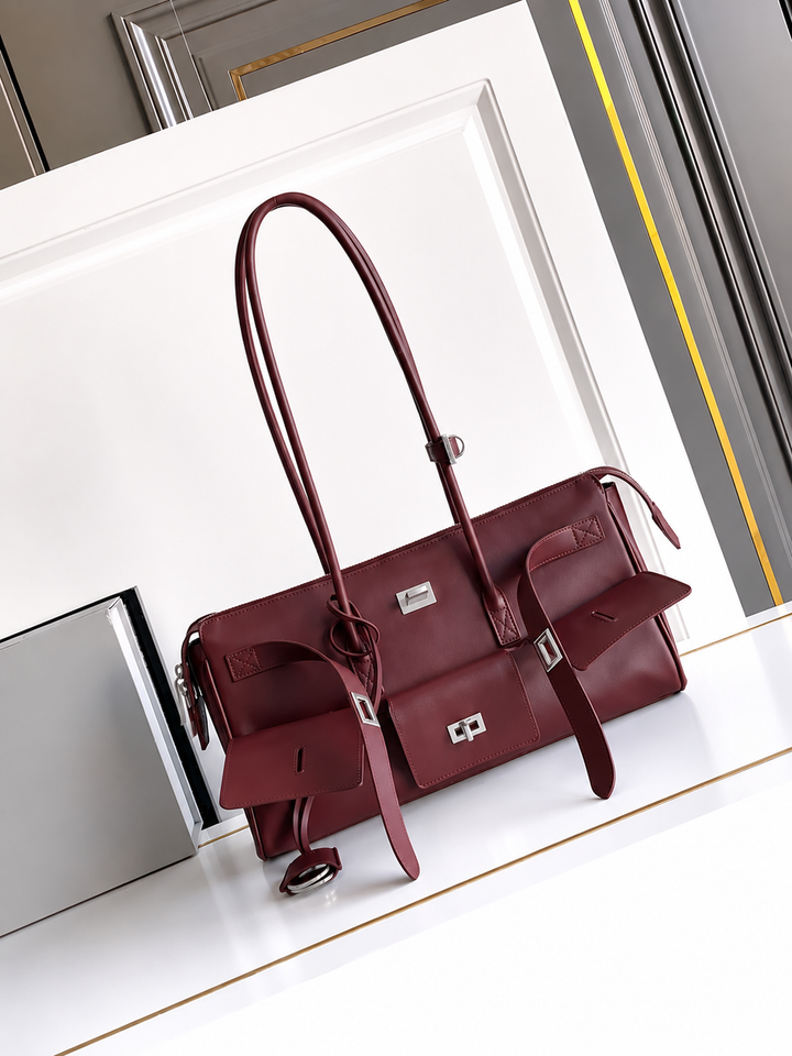 Maroon handbag with gold accents on a white surface