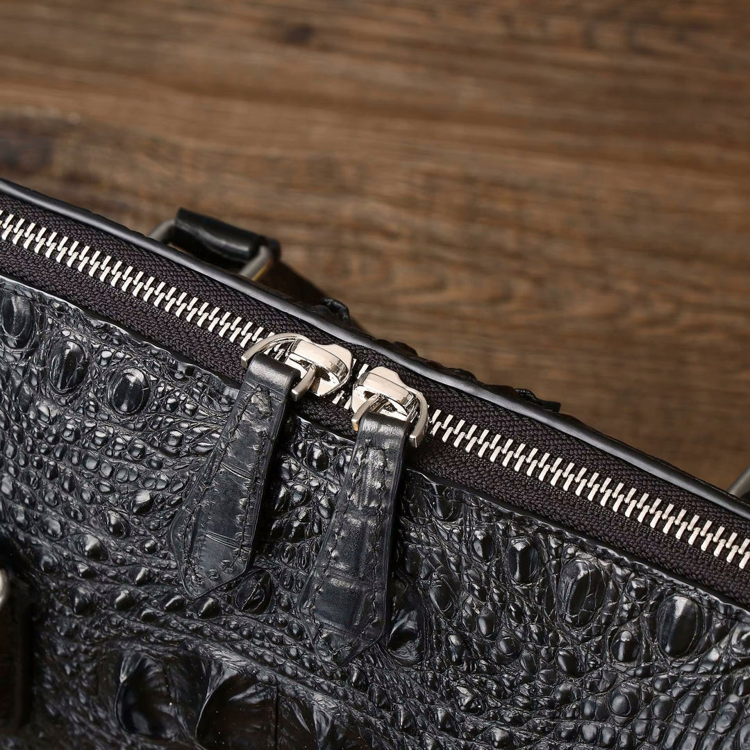 Silver zip closure and dual handle hardware close-up detail on croc-embossed leather briefcase
