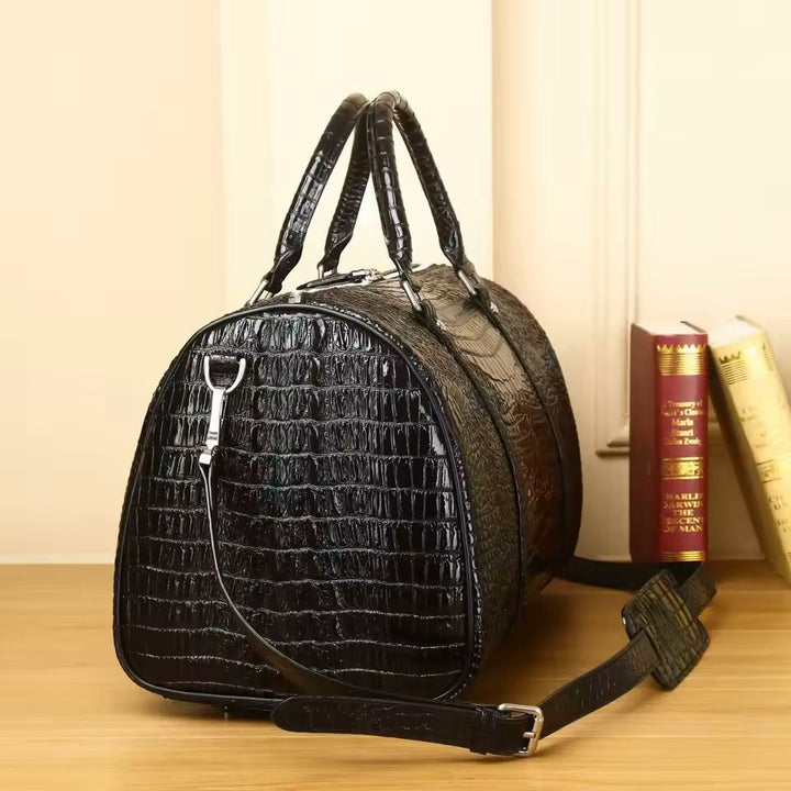 Large croc-embossed leather travel bag side view showing cylinder silhouette and shoulder strap
