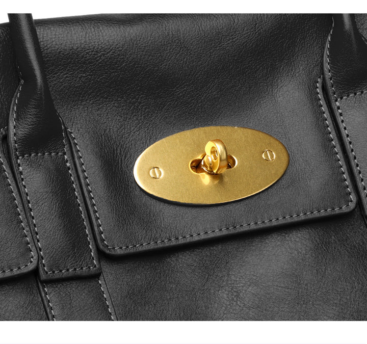 Black leather handbag with a gold plaque featuring a heart design.