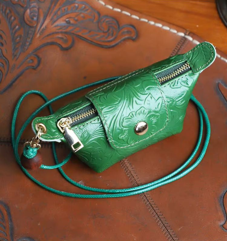 Black floral-embossed genuine leather mini dumpling bag lifestyle shot showing lanyard carry