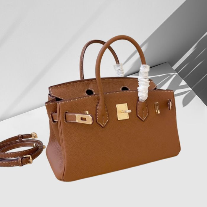 Brown handbag with gold hardware on a light gray background