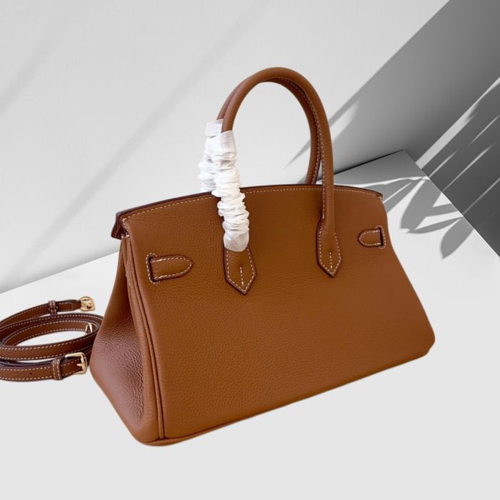 Brown leather handbag with a strap on a light background