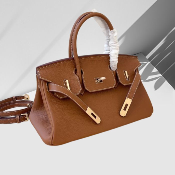 Brown handbag with gold hardware on a light gray background