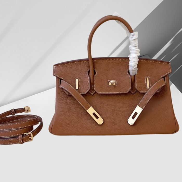 Brown leather handbag with gold hardware on a white background