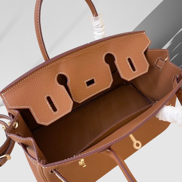 Brown leather handbag with gold hardware on a light gray background