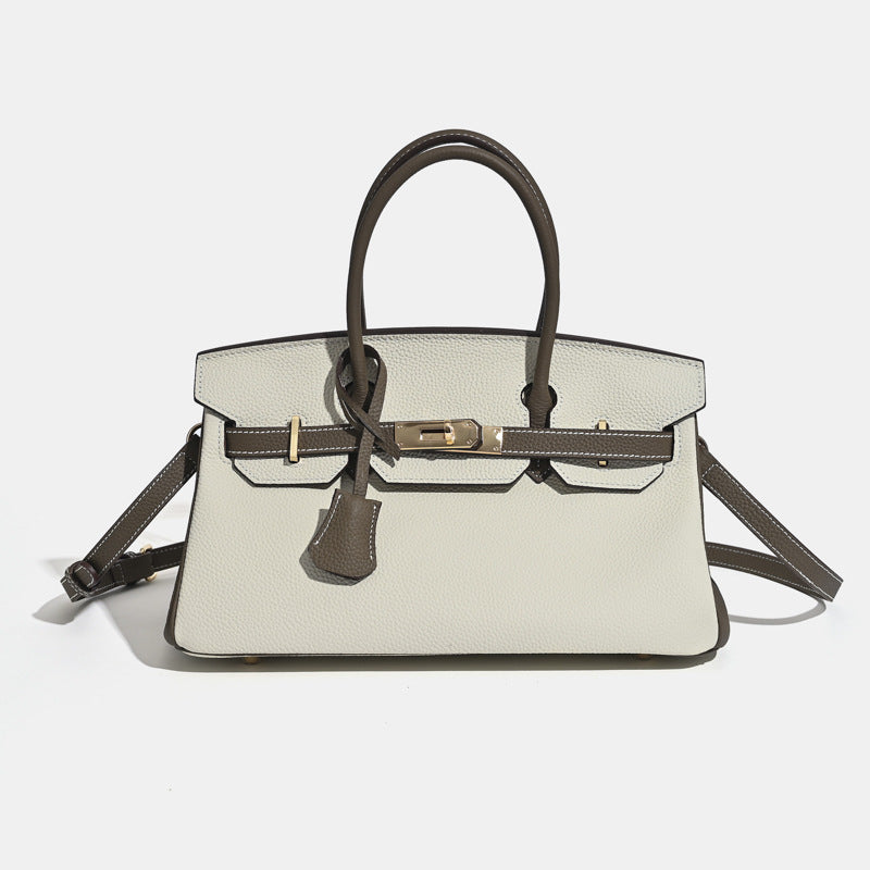 Full-grain leather handbag flap cover detail with gold turn-lock closure close up
