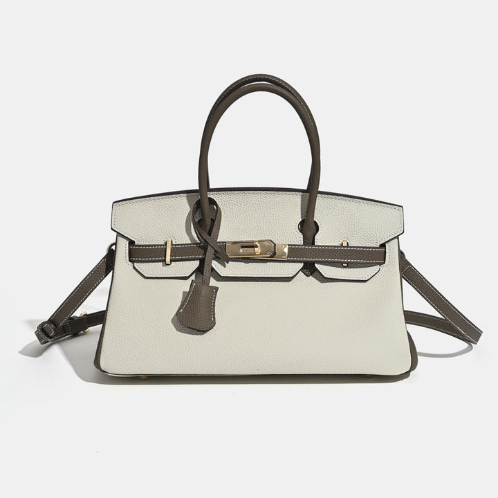 Full-grain leather handbag flap cover detail with gold turn-lock closure close up