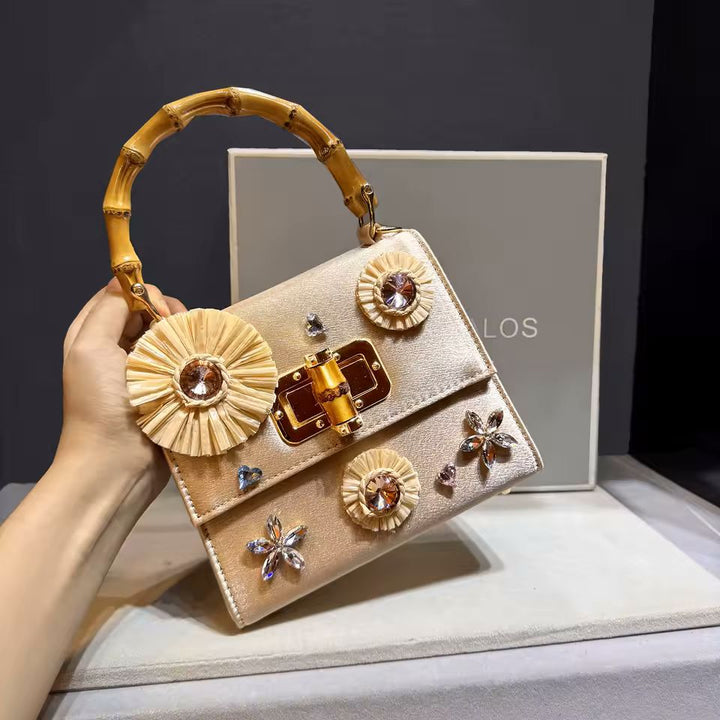 Square leather box bag side view showing bamboo knot handle and crystal flower embellishments