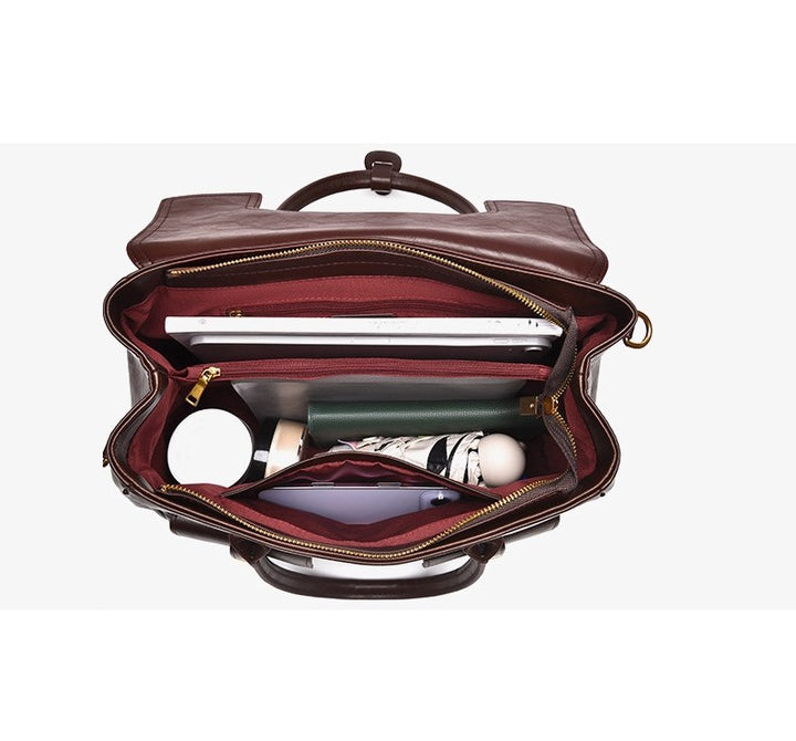 Brown leather bag with gold zipper partially open, showing a laptop and other items on a white background