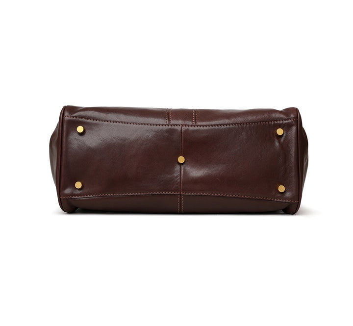 Brown leather toiletry bag with gold studs on a white background