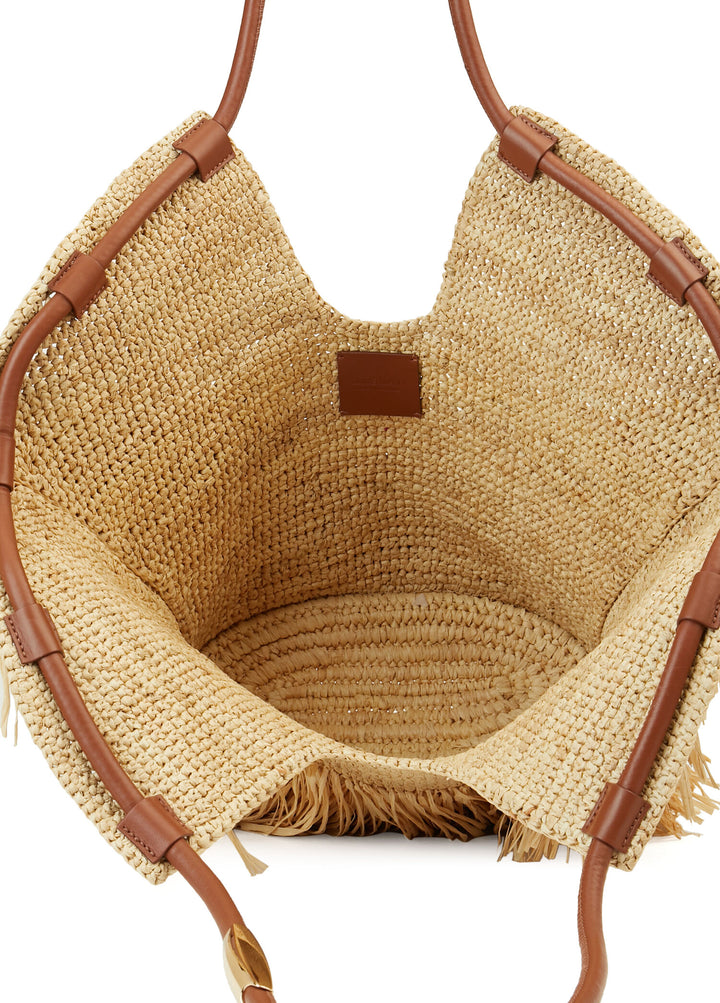 Woven basket with brown leather handles on a white background